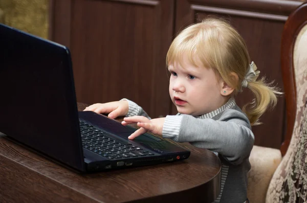 A little girl learns to type on the keyboard of the portable computer. The laptop