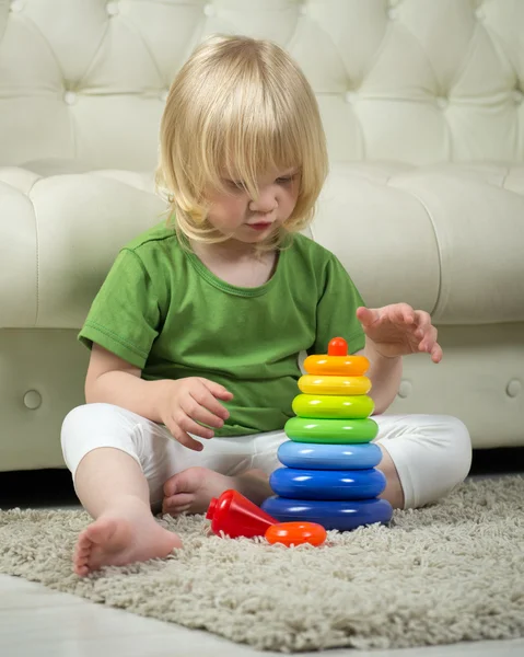 Educational game. A child plays with children\'s pyramid. The pyramid is almost assembled.