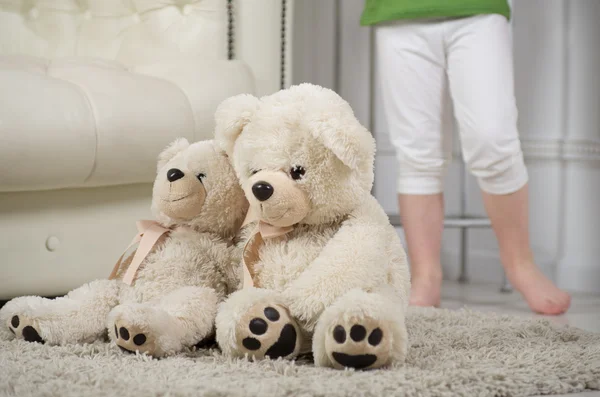 Toy polar bears sitting on the floor. On the back legs of a small child