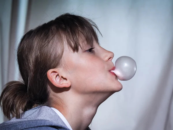Chewing gum. Portrait of a girl. Inflates a bubble from chewing gum