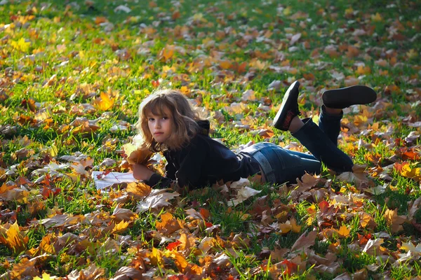Girl with the book among the autumn leaves