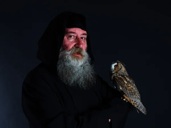 Magician, an alchemist, an old man with a bird owl on his shoulder. Monk. Mysticism, fantasy, fairy tale.