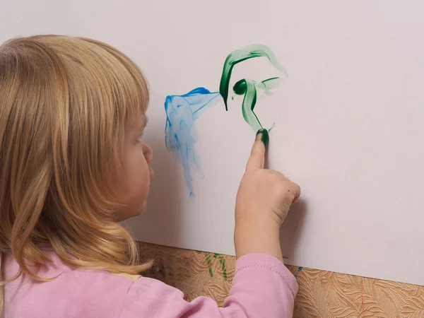 Small child draws a finger paints on a large white sheet of paper. Finger paint for the little children.