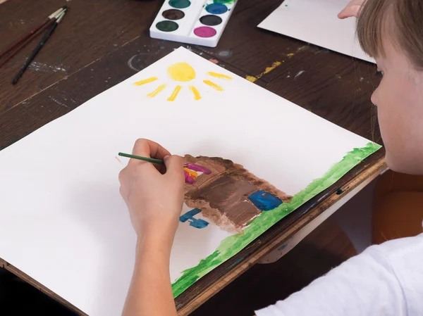 The child draws house and sun