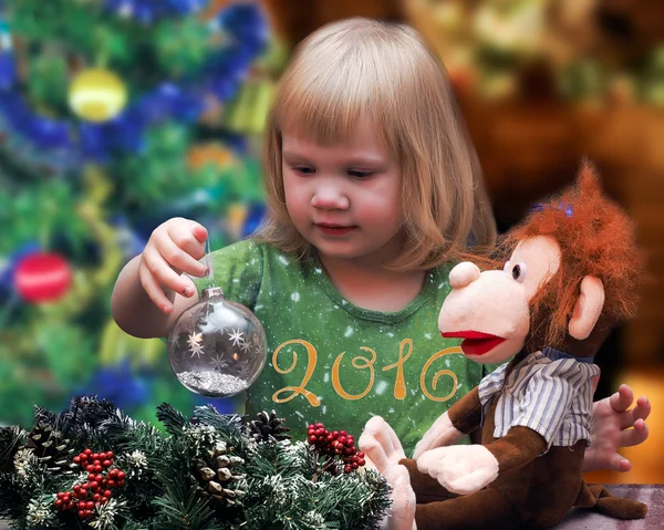 A child with a toy monkey at the Christmas tree