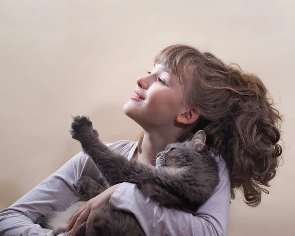 Girl and a cat. The girl smiles, holds a cat\'s paw