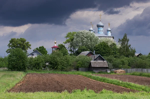 The church in the village. Plow the garden. Rain, clouds in the sky