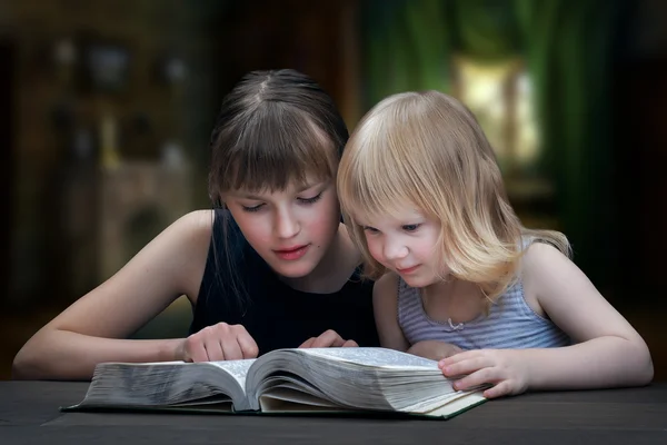 Children reading the book. Two girls, two sisters together.
