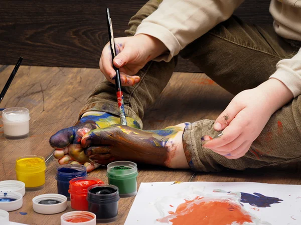 A child paints paint bare feet