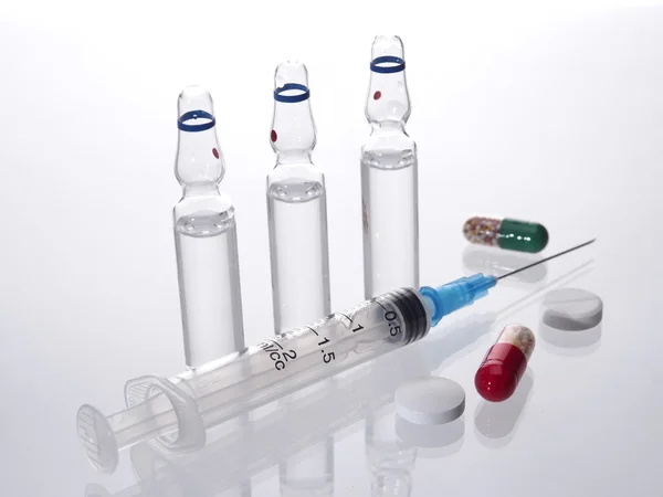 Medical vials for injection syringe and bright tablets, capsules on a white background