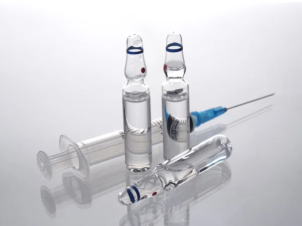 Group of ampoules and injection syringe on a white background.