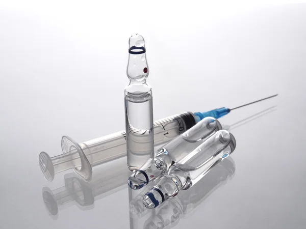 Group of ampoules and injection syringe on a white background.