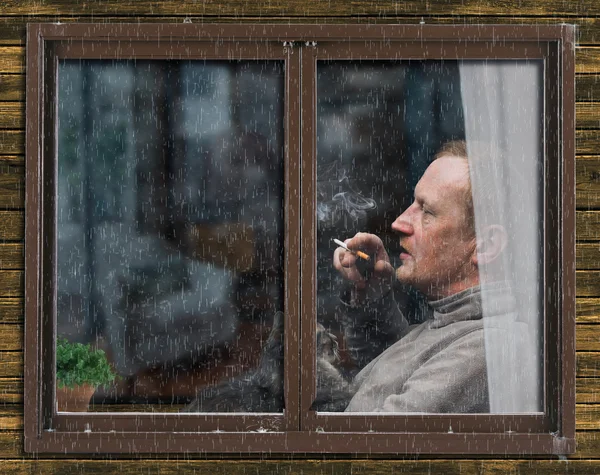 Rain, the window of the apartment. Outside, the profile of a man with a cat in her arms