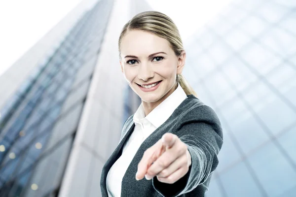 Businesswoman looking and pointing at camera