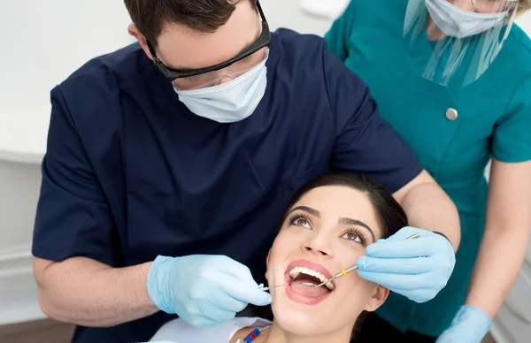 Dentist examining female patient mouth