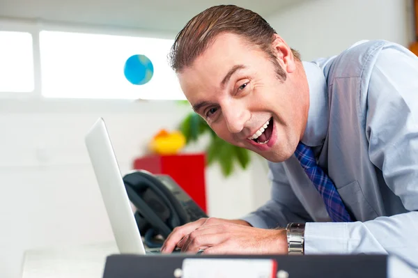 Excited businessman working on laptop