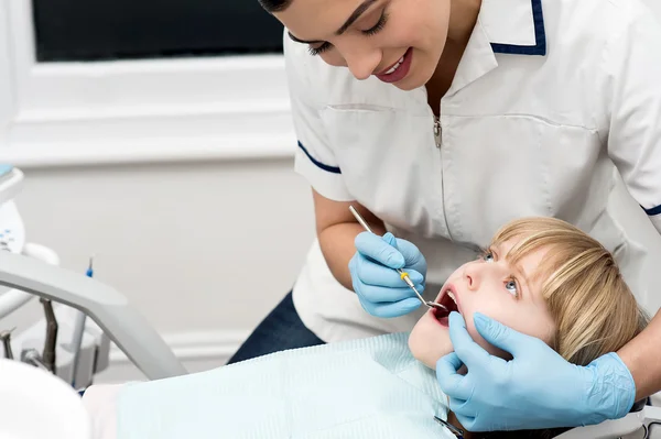 Professional dentist inspecting kid\'s teeth