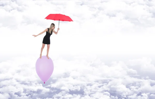 Girl with a red umbrella walking barefoot on a balloon flying in
