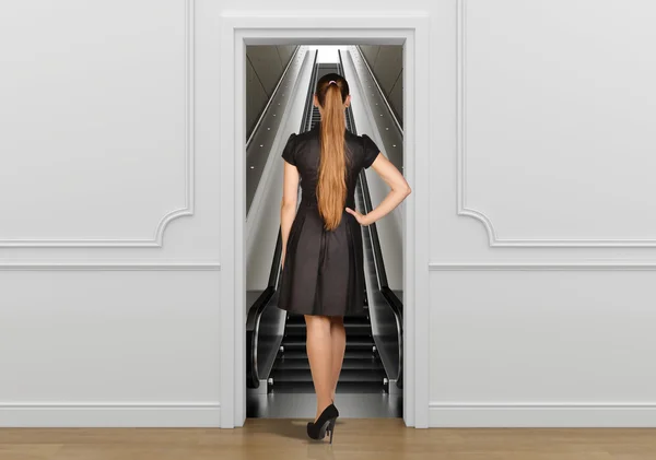 Girl standing back to doorway going on escalator