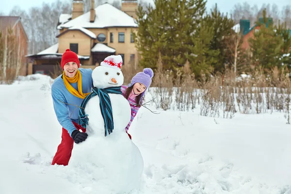 Father and daughter with snowman