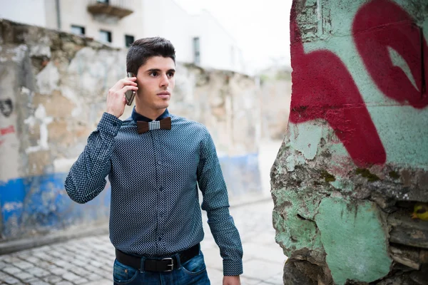 Man with shirt and jeans talking by phone and walking