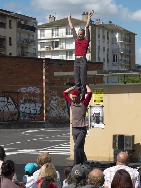 Female acrobat standing on the shoulders of his partner in the street .