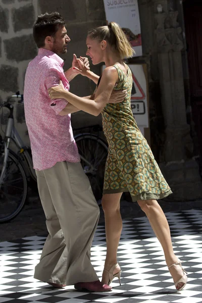 Couple dance in the street on a ckeckered ground.