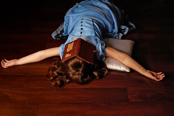 Little girl lying on the floor covered his face with a book