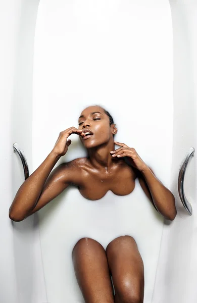 Black woman  in a bath with milk