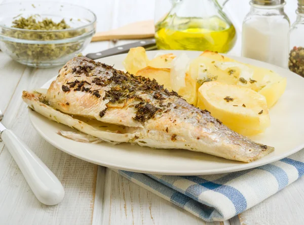 Baked sea bass with potatoes in tray