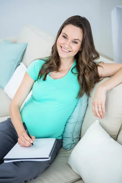 Pregnant woman writing on document