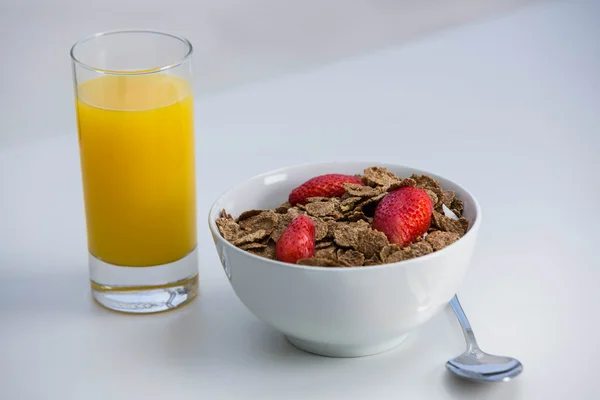 View of bowl of cereals and orange juice