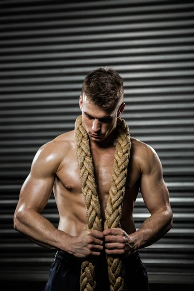 Shirtless man with battle rope around neck