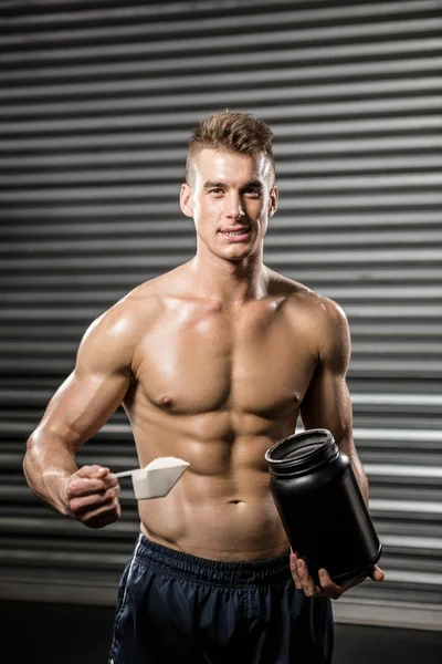 Shirtless man holding protein powder