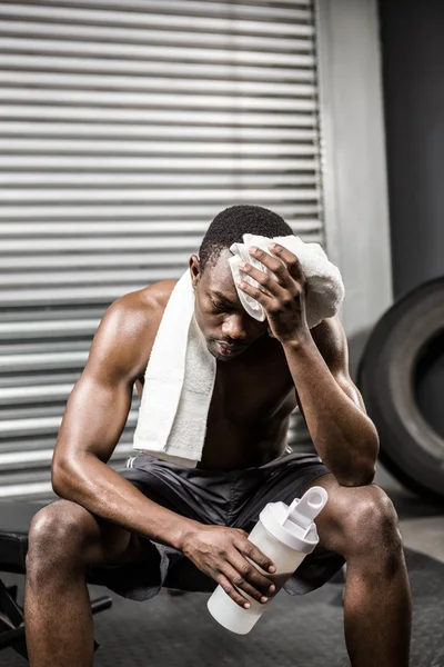 Shirtless man wiping sweat with towel