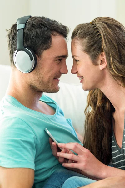 Young couple cuddling while listening to music on mobile phone