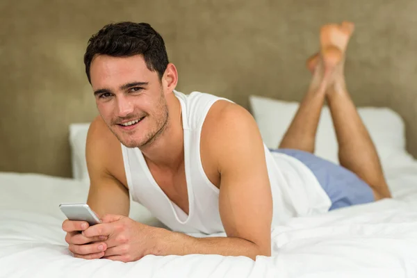 Young man lying on bed with his phone