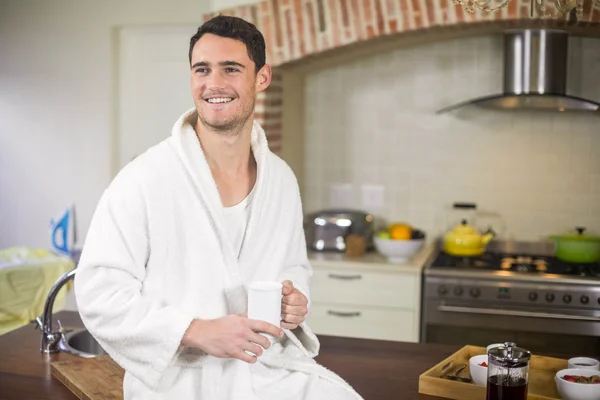 Young man in bathrobe holding a cup of tea