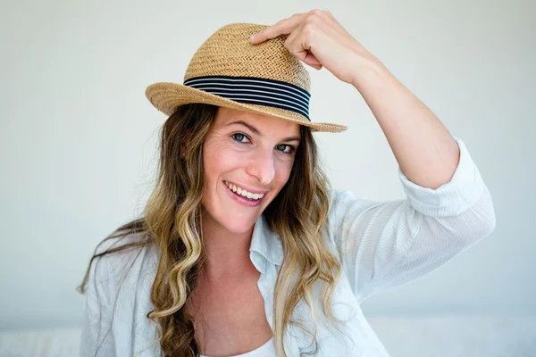 Woman wearing a straw fedora smiling into the camera