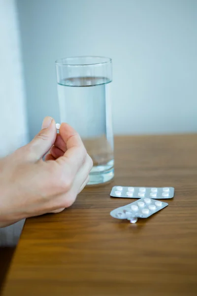 An open packet of pills next to a glass of water