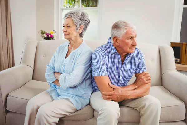 Sad senior couple sitting on sofa