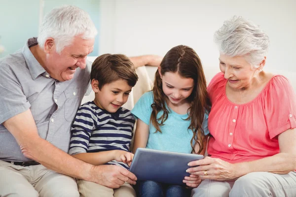 Couple using tablet with grand children
