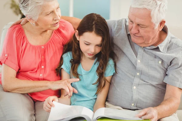 Grandparents reading book with granddaughter