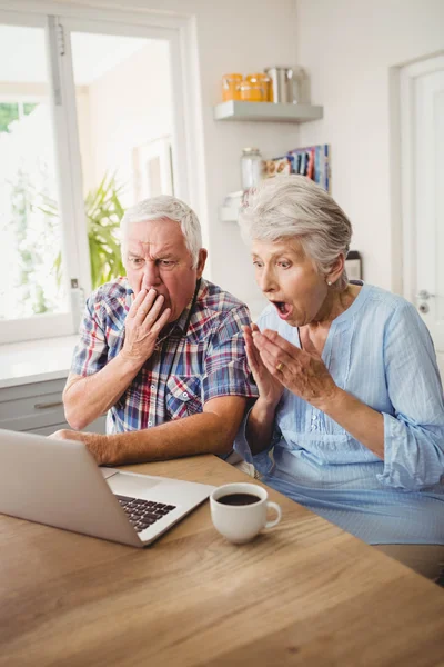 Surprised senior couple using laptop