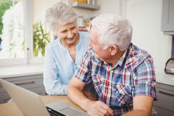 Senior couple talking while using laptop