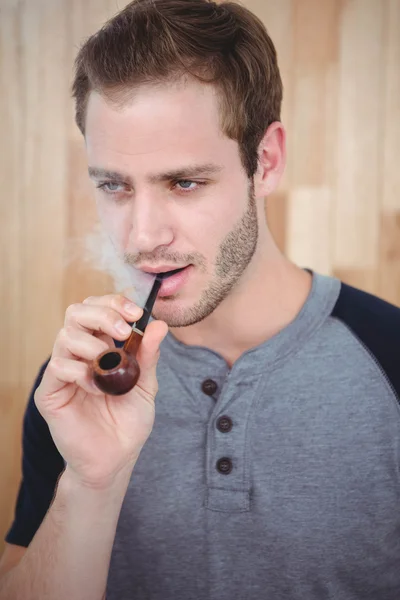 Handsome hipster smoking pipe