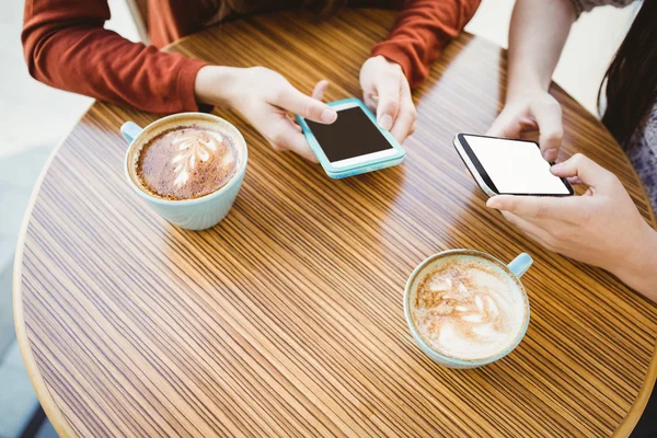 Friends using smartphone and having coffee