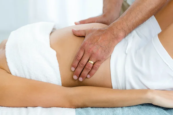 Pregnant woman receiving a stomach massage from masseur