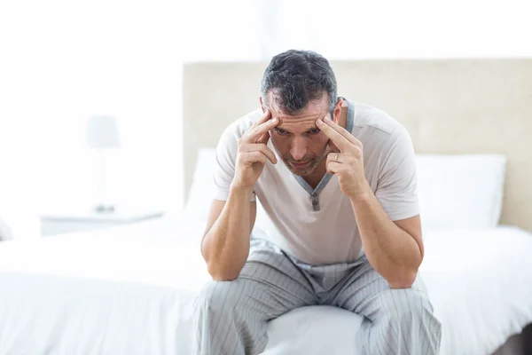 Worried man sitting on bed