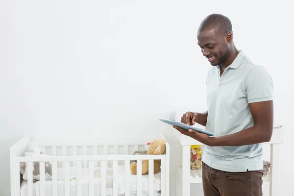 Smiling man standing next to a cradle